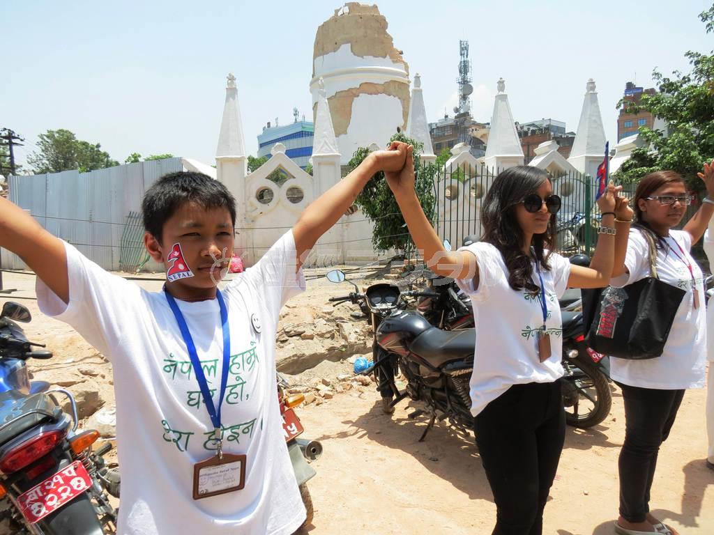 ５月２５日、倒壊した歴史的建造物、ダラハラ・タワーの周りで手をつなぎ、ネパールの復興を祈る若者ら＝２０１５年、ネパール・首都カトマンズ（岩田智雄撮影）