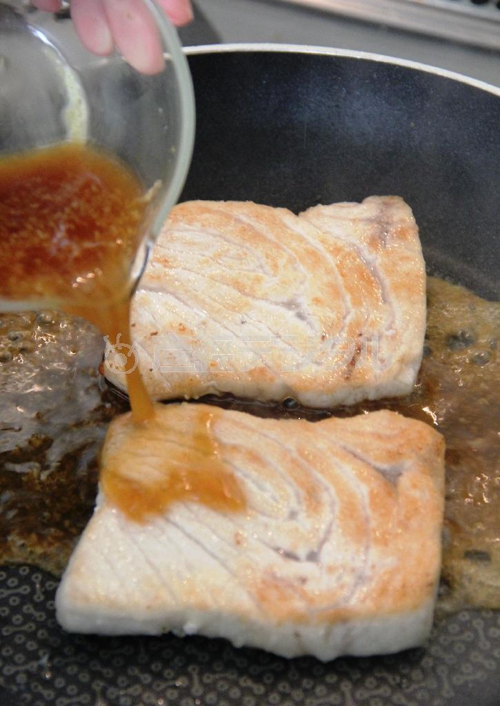 カジキのしょうが焼き（作り方３）＿＿余分な油をふきとり、［合わせ調味料：しょうゆ・酒・みりん＿各大さじ１、しょうが汁・砂糖＿各大さじ１／２］を回し入れてカジキに絡め、ピーマンと盛り合わせる（田中幸美撮影）