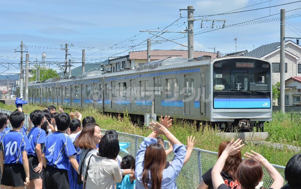 ＪＲ仙石線が全線で運行を再開し、石巻市立山下中学校の生徒らに見守られながら陸前山下駅に向かう電車＝２０１５年５月３０日、宮城県石巻市（宮崎瑞穂撮影）