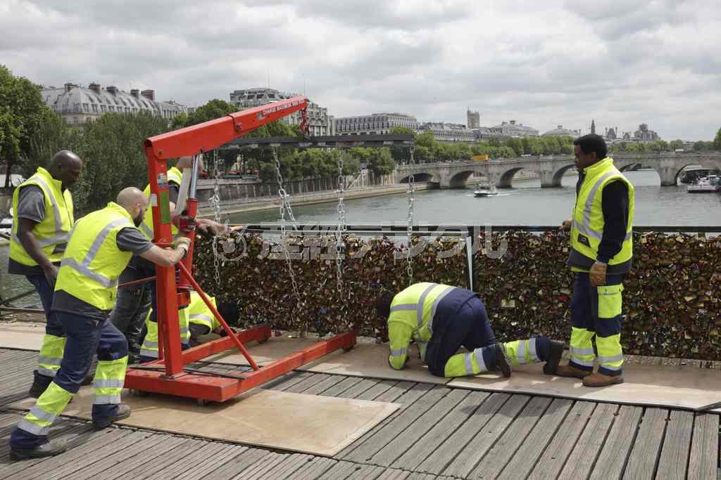 首都パリのセーヌ川に架かるポンテザール橋で始まった「愛の南京錠」の撤去作業。南京錠が鈴なりになったフェンスがクレーンで取り外された＝２０１５年６月１日、フランス（ロイター）