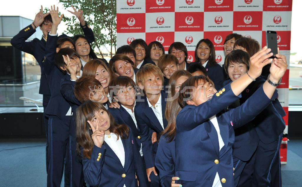 カナダへ出発前に大野忍の携帯電話で記念撮影するなでしこジャパンの選手たち＝２０１５年６月１日、千葉県成田市・成田空港（納冨康撮影）