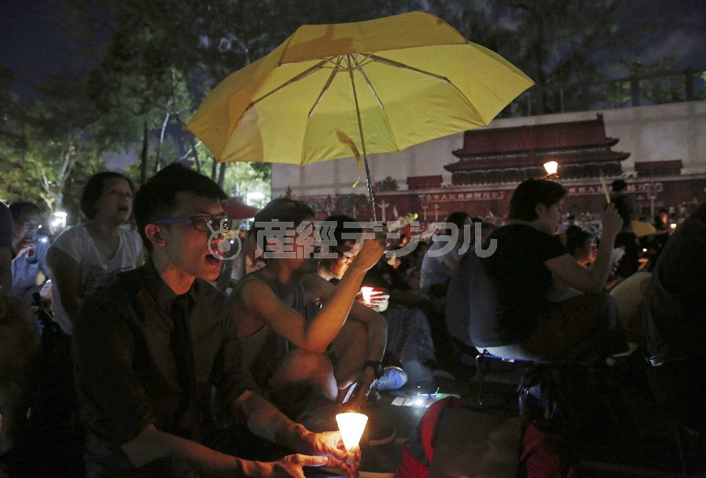 天安門事件から２６年となった６月４日夜、香港のビクトリア公園で行われた追悼集会に集まった若者たち。昨年の香港民主化デモの象徴となった黄色い雨傘を掲げる学生の姿もみられた＝２０１５年６月４日、中国・香港（ＡＰ）
