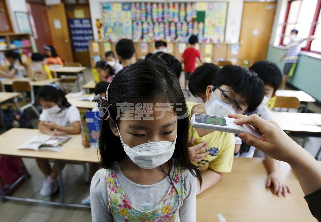 ソウル市内の小学校で、中東呼吸器症候群（ＭＥＲＳ）感染防止のため、マスク姿で体温のチェックを受ける児童＝２０１５年６月９日、韓国・首都ソウル（ロイター）
