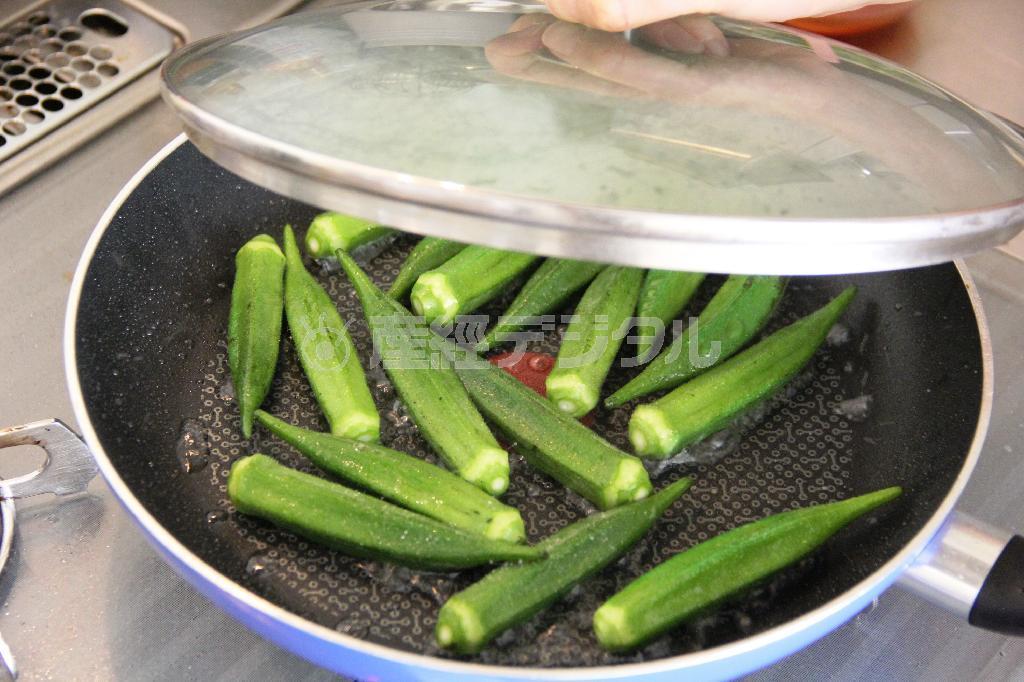 オクラとイカのピリ辛炒め（作り方１）＿＿サラダ油の半量を熱し、オクラを炒める。塩をふって水を回し入れ、蓋をして蒸し煮にする。ざるにあけ、水けをきる。