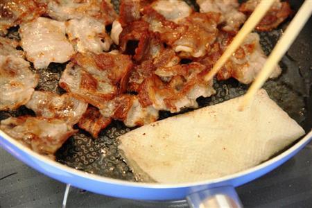 トマトのカリカリ豚のっけサラダ（作り方１）＿＿オリーブ油を熱し、豚バラ肉を入れカリカリに焼く。余分な脂をふきとり、塩、粗びきこしょうをふる。