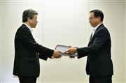 浜岡原発３号機の再稼働を目指し、原子力規制庁の担当者（左）に申請書類を提出する中部電力の増田博武原子力部長＝１６日午前、東京都港区