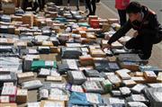 山西省太原市で大学前の路上に置かれた宅配便の中から自分のものを探す大学生。いつでも便利に宅配便が受け取れるように、最近ではさまざまなサービスが登場している（中国新聞社）