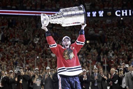 優勝杯「スタンリー・カップ」を掲げるブラックホークスの選手＝２０１５年６月１５日、米イリノイ州シカゴ（ＡＰ）