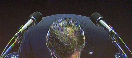 シャープの株主総会で、巨額赤字に関し謝罪する高橋興三社長のモニター画像。株主からは厳しい質問が相次いだ＝２３日午前、大阪市