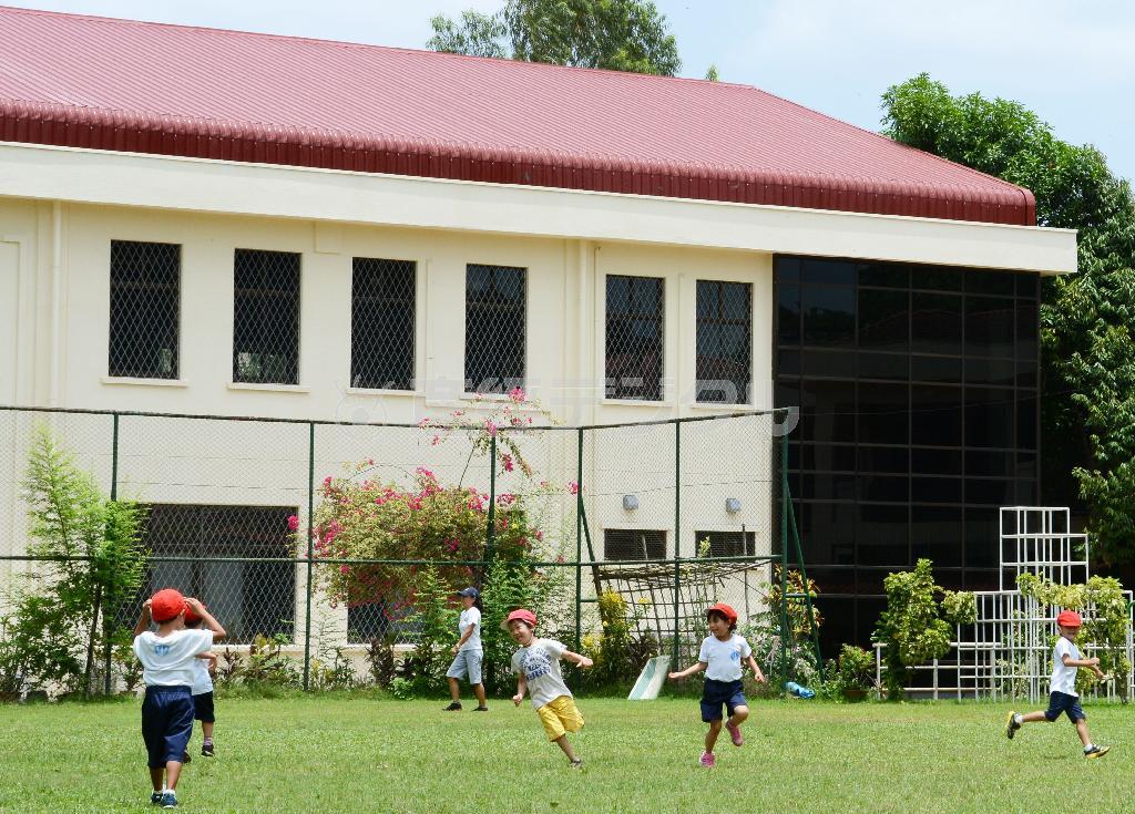ミャンマーの最大都市ヤンゴンにある日本人学校の新校舎。手前は校庭で遊ぶ幼稚部の児童ら＝２０１５年５月（共同）