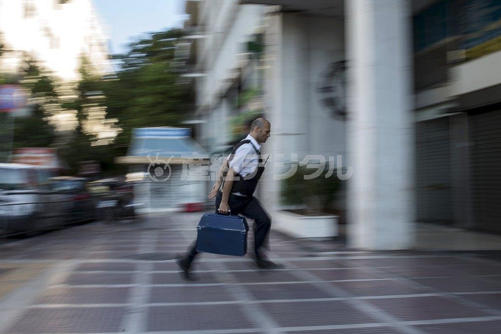 ６月２８日、現金自動預払機（ＡＴＭ）に紙幣を補充するため、首都アテネの銀行前でダッシュする警備員。デフォルトの可能性が高まったギリシャではこの日、多くの預金者たちが口座の凍結を懸念してＡＴＭで現金を引き出し、各地のＡＴＭで紙幣が不足する事態となった＝２０１５年（ロイター）