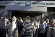 シャッターの閉まった銀行の前で、通常は月末に支給される年金の支払を待つ受給者たち＝２０１５年６月２９日、ギリシャ・首都アテネ（ＡＰ）