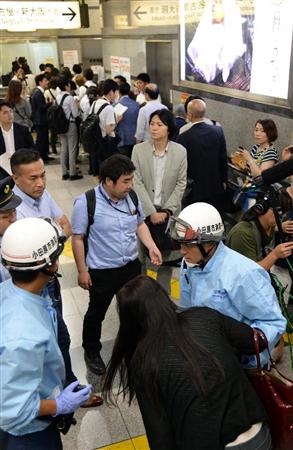 車内で火災が発生した東海道新幹線が小田原駅に到着。気分が悪いという女性（手前）を誘導する消防隊員ら＝３０日午後、神奈川県小田原市（鴨川一也撮影）