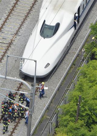 緊急停止した東海道新幹線「のぞみ２２５号」の車内でしゃがみ込む乗客（左）＝３０日午後０時３４分、神奈川県小田原市