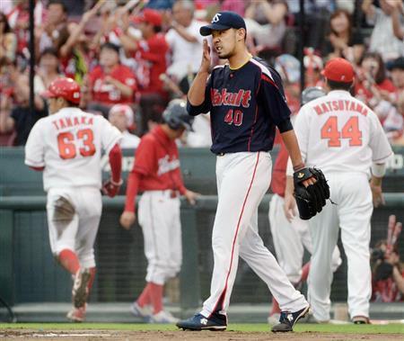 一回、広島・会沢（あいざわ）翼の適時打で田中広輔（左奥）が生還、追加点を許し顔をしかめるヤクルト先発の古野（ふるの）正人（手前）＝２０１５年７月３日、広島県広島市南区・マツダスタジアム（共同）