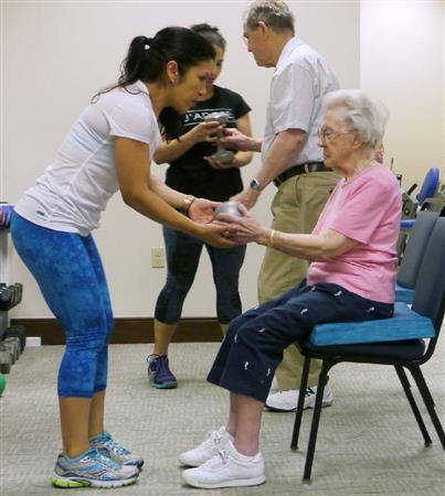 米東部の継続的なケア付き退職者コミュニティー（ＣＣＲＣ）「チャールズタウン」のジムでインストラクターの指導を受ける入居者ら＝２０１５年６月１２日（共同）