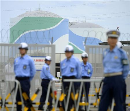 原子炉に核燃料の装填作業が行われる九州電力の川内原発１号機（奥左）。手前は抗議行動を警戒する警備員ら＝７日午前、鹿児島県薩摩川内市