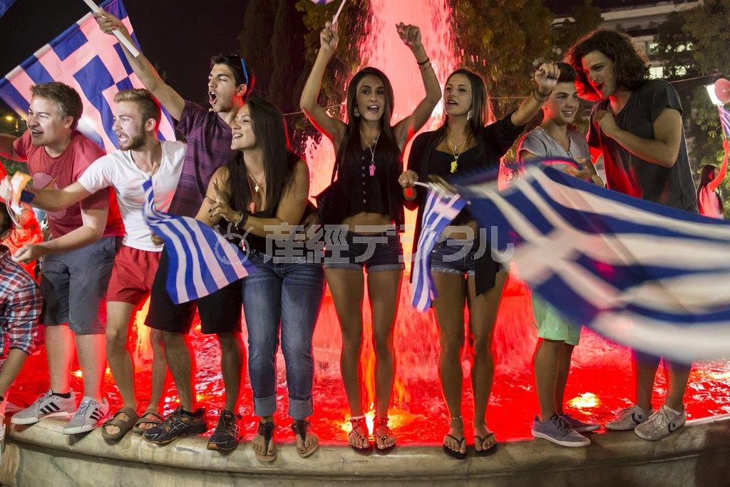 ギリシャの国旗を振って、財政再建策への「反対」が多数を占めた国民投票の結果を喜ぶ若者たち＝２０１５年７月５日、ギリシャ・首都アテネ（ロイター）