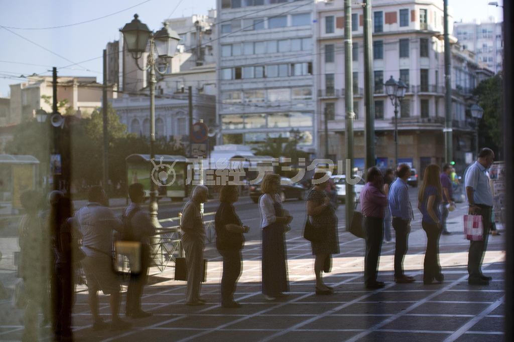 ７月８日、ギリシャ・首都アテネの銀行の窓に映った、ＡＴＭに並ぶ市民＝２０１５年（ＡＰ）