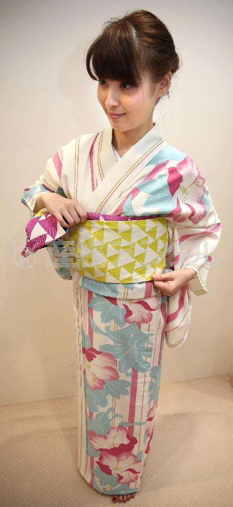 リボン返し（手順６）＿＿作った帯結びが後ろの正面になるように、襟の向きに沿って右方向に回していく＝２０１５年７月２日、東京都中央区銀座（福島範和撮影）