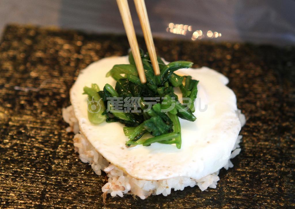 目玉焼き＆ホウレンソウのお浸しのおにぎらず（作り方３）＿＿ラップの上にのりを乗せ、調理したごはんの半量を乗せ、調理したホウレンソウをまんべんなく広げる（田中幸美撮影）