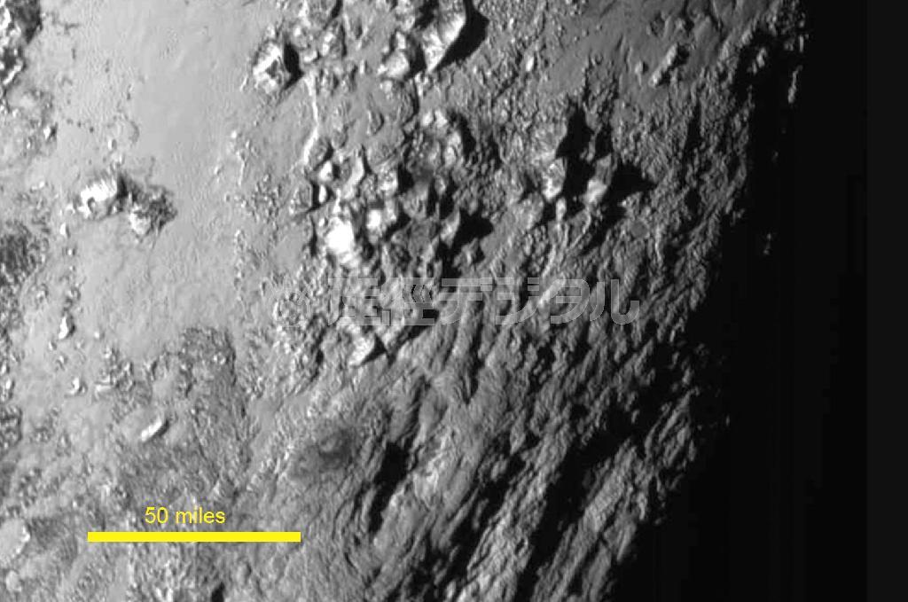 探査機ニューホライズンズが７月１４日に撮影した冥王星の地表。高さ約３５００メートルもの山々（中央）が集まり、近くにクレーターのない平地が広がっている（左下のスケールは約８０キロ、ＮＡＳＡ提供・共同）