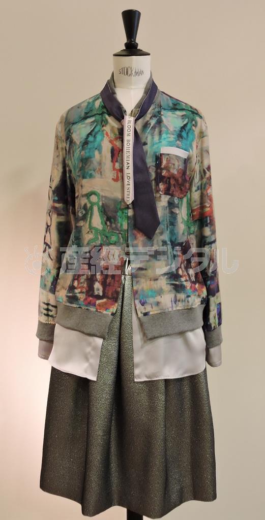ロンドンの街角をイメージしたプリント柄のブルゾン「ＦＩＧＬＩＯ」（４万９０００円）は、袖口と裾から魅せるシルバーグレーのサテンが重ね着に見えるデザイン。ラメ入りスカート「ＡＣＥ」（３万５０００円）がよく映える。ネクタイは参考商品＝２０１５年７月１０日、東京都渋谷区（藤沢志穂子撮影）