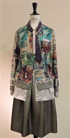 ロンドンの街角をイメージしたプリント柄のブルゾン「ＦＩＧＬＩＯ」（４万９０００円）は、袖口と裾から魅せるシルバーグレーのサテンが重ね着に見えるデザイン。ラメ入りスカート「ＡＣＥ」（３万５０００円）がよく映える。ネクタイは参考商品＝２０１５年７月１０日、東京都渋谷区（藤沢志穂子撮影）