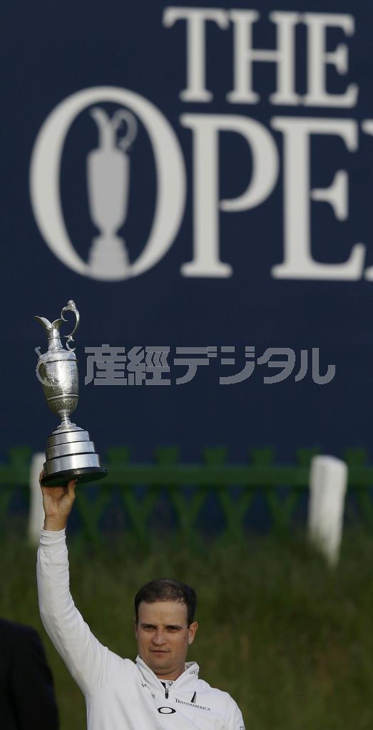 悲願の全英優勝カップを手にしたザック・ジョンソン。後方の大会看板は、ただ「Ｔｈｅ＿ＯＰＥＮ」とある＝２０１５年７月２０日、英スコットランド・セントアンドルーズ（ロイター）