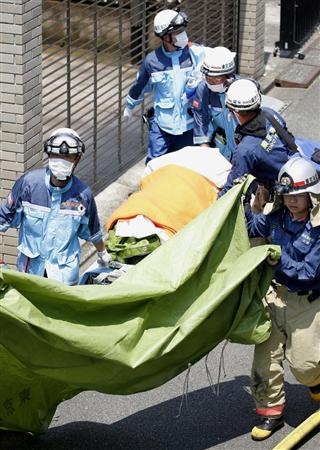 軽飛行機が墜落した現場で搬送作業に当たる消防隊員＝２６日午後０時１７分、東京都調布市