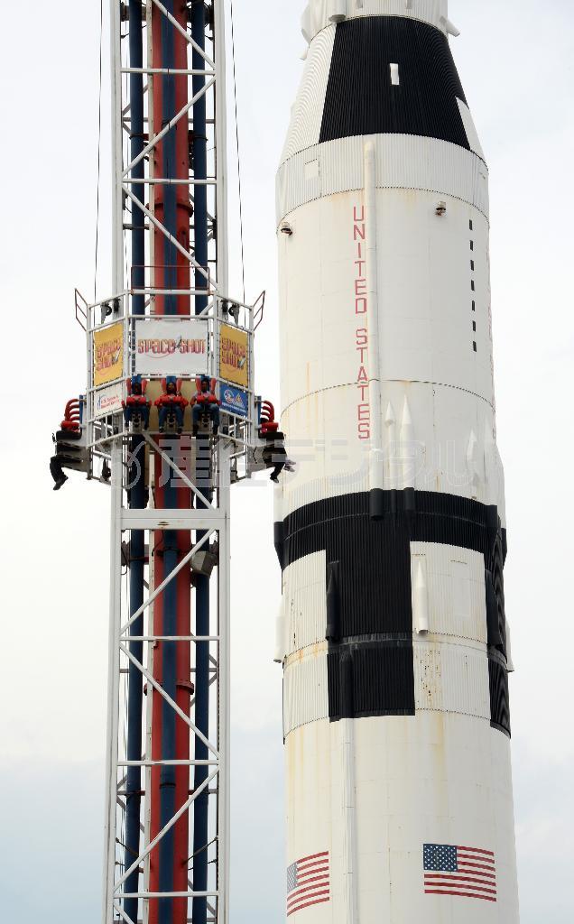 サターンＶ型ロケット（左）と絶叫マシーンの競演。約１１０メートルものロケットの高さを実感できる＝２０１５年３月２６日、米アラバマ州ハンツビルのアメリカ宇宙ロケットセンター（川口良介撮影）