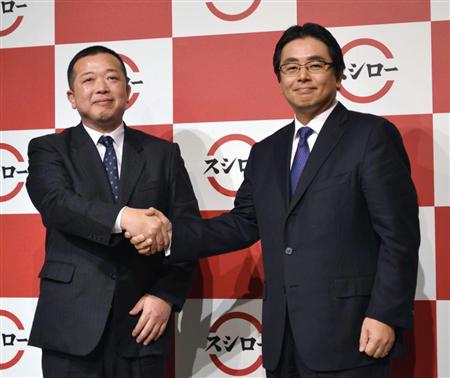 あきんどスシローの水留浩一社長（右）は、前社長の豊崎賢一氏と握手を交わし、事業拡大を誓った＝２０１５年１月、東京都港区