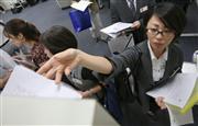 ２０１５年４～６月期の決算発表がピークを迎え、報道各社の棚に資料を配る各企業の担当者ら＝３１日、東京都中央区の東京証券取引所