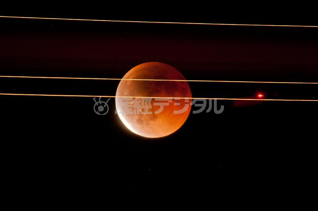 「皆既光跡」。皆既月食を撮影中に前をジェット機が横切ったのを撮影。ジェット機の尾翼に点いているライトが線になり、パッシングするように光っているライトが点となって写った。月を横切るものは邪魔者扱いされるが、必ずしもそうではない＝北海道の千歳空港近く（遠藤湖舟さん撮影）。（Ｃ）Ｋｏｓｈｕ＿ＥＮＤＯ
