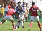 トンガ戦の前半、タックルを受ける日本代表の主将、リーチ・マイケル（中央）。奥は伊藤鐘史（しょうじ）＝２０１５年８月３日、カナダ・ブリティッシュコロンビア州バーナビー（共同）