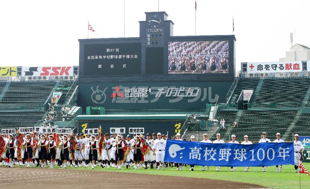 第９７回全国高校野球選手権大会の開会式リハーサルで「高校野球１００年」の横断幕を手に行進する選手たち＝２０１５年８月５日午前、東京都西宮市・甲子園球場（共同）