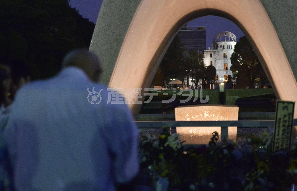被爆から７０年を迎え、原爆慰霊碑前で祈る男性。奥は原爆ドーム＝２０１５年８月６日午前、広島県広島市中区中島町の平和記念公園（共同）