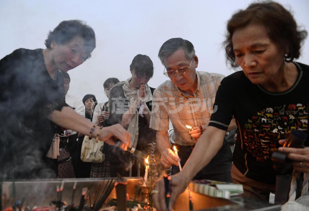 原爆慰霊碑の前でろうそくをともし、犠牲者を追悼する人たち＝２０１５年８月６日早朝、広島県広島市中区中島町の平和記念公園（共同）