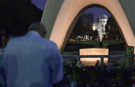 被爆から７０年を迎え、原爆慰霊碑前で祈る男性。奥は原爆ドーム＝２０１５年８月６日午前、広島県広島市中区中島町の平和記念公園（共同）