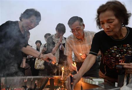 原爆慰霊碑の前でろうそくをともし、犠牲者を追悼する人たち＝２０１５年８月６日早朝、広島県広島市中区中島町の平和記念公園（共同）