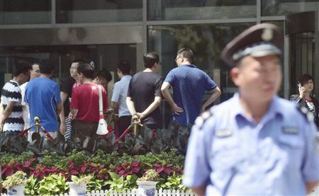 中国証券監督管理委員会の前に集まった個人投資家ら（奥）＝１３日、北京（共同）