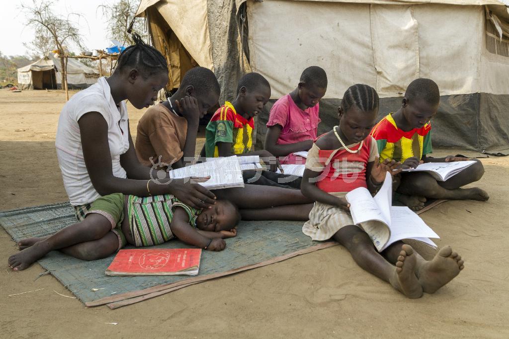 テントの外で本を広げる子供たち。両親は南スーダンから戻らず、兄弟だけで暮らしている＝２０１５年６月１９日、エチオピア・ガンベラ州（ワールド・ビジョン・ジャパン撮影）