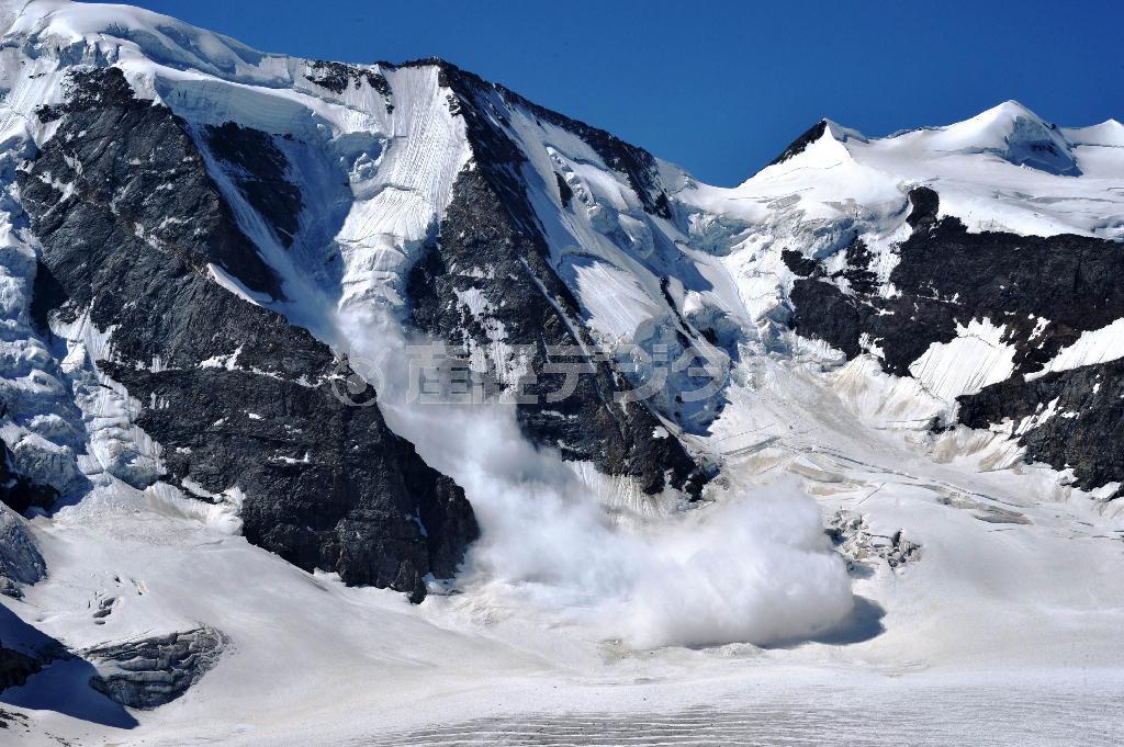 ベルニナ・アルプスのピッツパリュー峰（３９０１メートル、左）の雪庇（せっぴ）が大音響とともに崩れ、氷河を雪煙で覆った瞬間＝２０１５年７月１１日（唐木英明さん撮影）