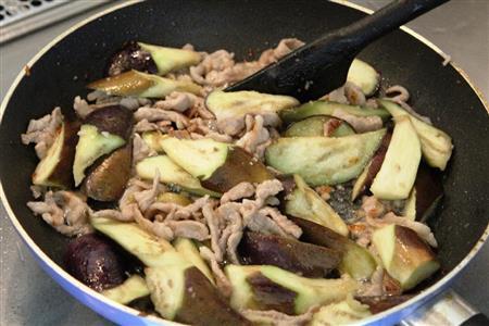 ナスと豚肉のバジル炒め（作り方２）＿＿トマトを加えて中火で炒め煮して、ナンプラー、しょうゆ、塩、こしょうで味を整える。バジルを加えさっと混ぜる。