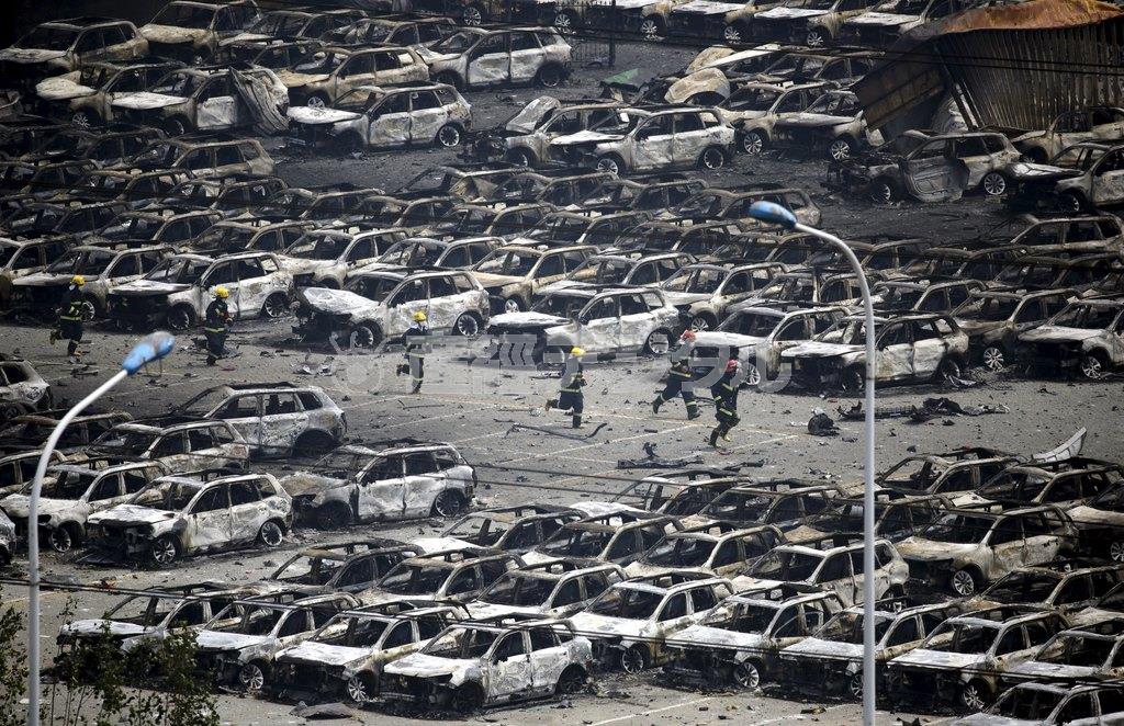 丸焦げになった自動車が並ぶ輸出サイトを捜索する消防隊員＝２０１５年８月１４日、中国・天津市（ロイター）