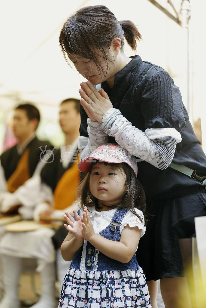 終戦から７０年を迎え、千鳥ケ淵戦没者墓苑で手を合わせる女性と子供＝２０１５年８月１５日午前、東京都千代田区三番町（共同）