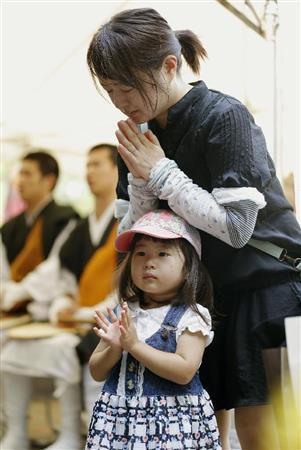 終戦から７０年を迎え、千鳥ケ淵戦没者墓苑で手を合わせる女性と子供＝２０１５年８月１５日午前、東京都千代田区三番町（共同）