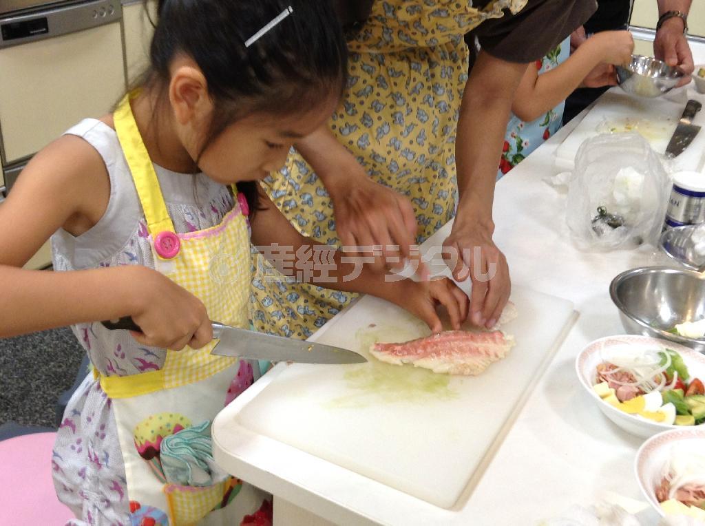 母親に教わりながら、慣れない手つきで「愛鯛」の切り身に包丁を入れる女の子＝２０１５年８月９日（日本財団撮影）