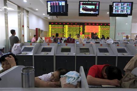 中国・上海市の証券会社の株価モニターの前に突っ伏す投資家ら＝２０１５年８月２４日（ロイター）