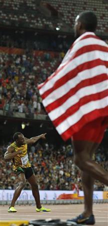 ０．０１秒の残酷。王座を守り弓矢のポーズをみせるウサイン・ボルト（左）と、国旗を羽織り肩を落とすジャスティン・ガトリン＝２０１５年８月２３日、中国・首都北京市の国家体育場（ＡＰ）